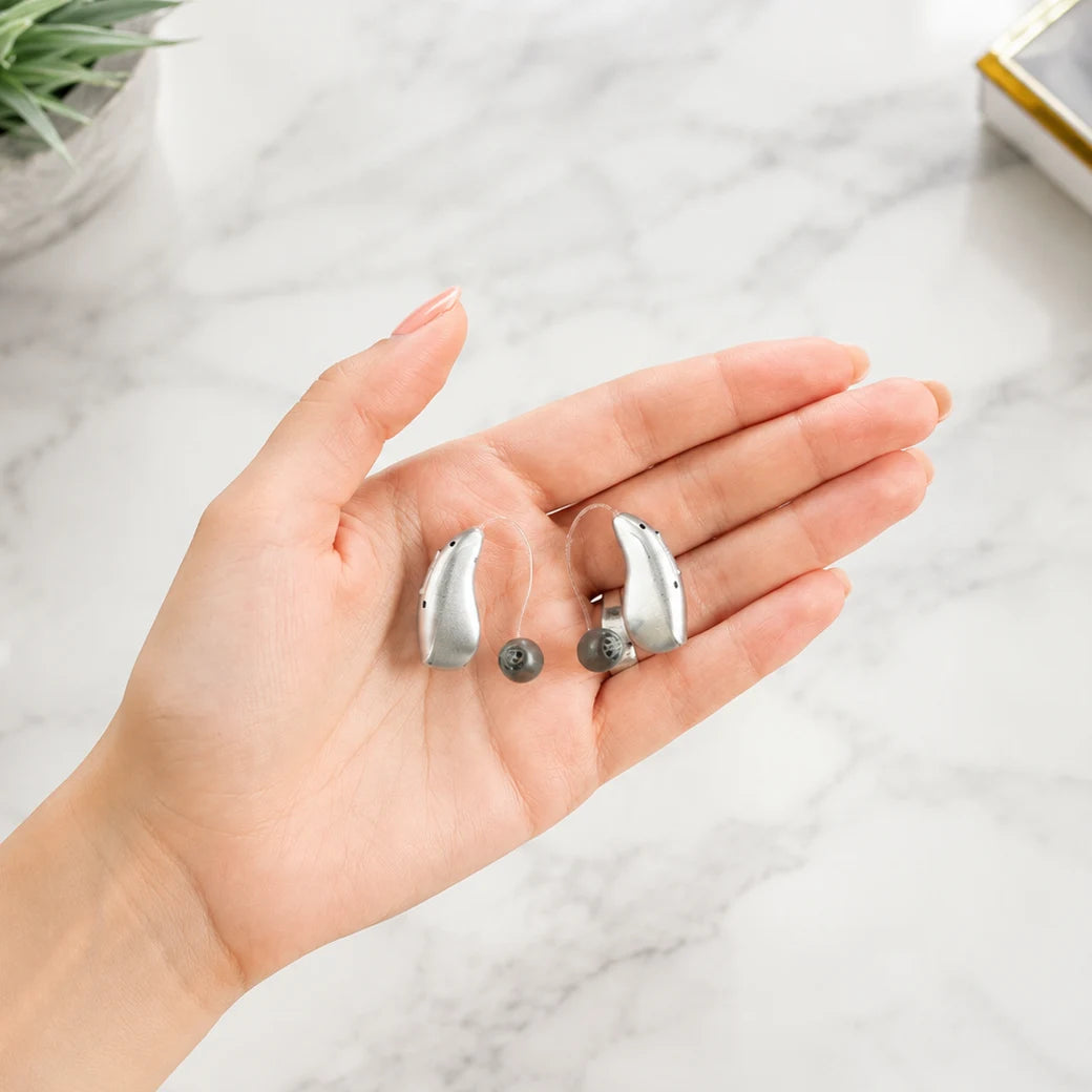 Small hearing aids resting in a hand